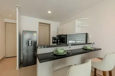 a kitchen with a counter with chairs and a refrigerator at Premium con ubicación excelente en Bocagrande in Cartagena de Indias