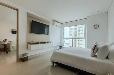 a white bedroom with a large bed and a flat screen tv at Premium con ubicación excelente en Bocagrande in Cartagena de Indias