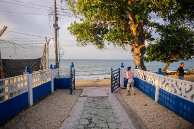 a woman sitting on a fence near the beach at Cabaña Playa Azul in Coveñas