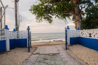 a gate to the beach with a tree and the ocean at Cabaña Playa Azul in Coveñas