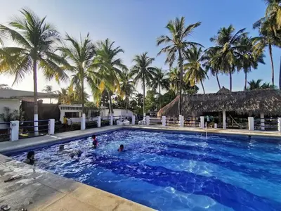 a large swimming pool with palm trees in the background at Apartamento frente al mar in Coveñitas