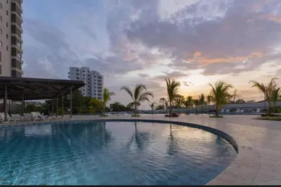 a large swimming pool with palm trees and a sunset at New luxury studio apartment with ocean view, Santa Marta in Simón Bolivar
