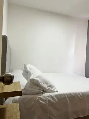 a white bed with white sheets and a wooden table at Moderno Rincón Urbano in Cartagena de Indias