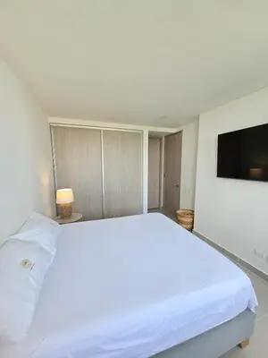 a bedroom with a white bed and a flat screen tv at Estilo y confort en cartagena, a pasos del mar in Cartagena de Indias