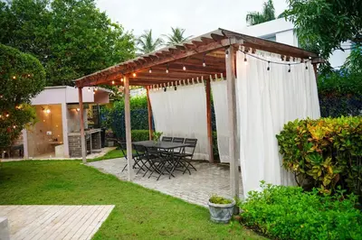 a pergola with a table and chairs in a yard at Cabaña privada con piscina y jacuzzi junto al mar in Santa Veronica