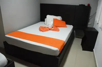 a bedroom with a bed with an orange towel on it at Hotel San Marcos Barranquilla in Barranquilla