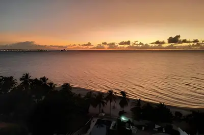 a sunset over the ocean with a boat in the water at Apartamento de playa privada in Santa Marta