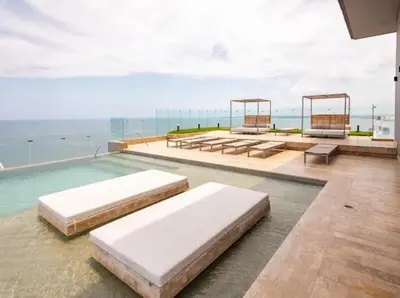 a swimming pool with beds and the ocean in the background at Loft cercano al Centro Histórico-Cartagena in Cartagena de Indias