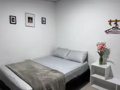 a white bedroom with a bed and a vase of flowers at CasaMartina in Cartagena de Indias