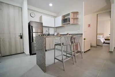 a kitchen with a counter with stools and a refrigerator at Apartamento en Cartagena elegante con piscina in Manzanillo del Mar