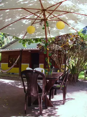 a wooden table and chairs under an umbrella at Coco Encantado Eco Hostal Camping in Cartagena de Indias