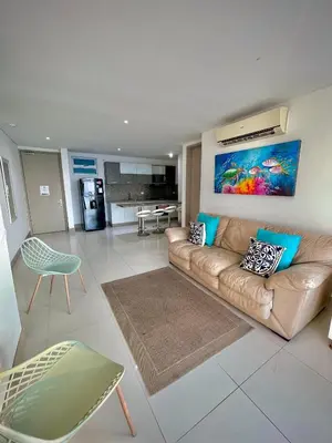 a living room with a brown couch and a kitchen at Apartamento de 2 Habitaciones Vista al Mar in Cartagena de Indias