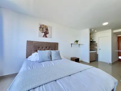 a white bedroom with a large bed with blue pillows at Apto 894 in Cartagena de Indias