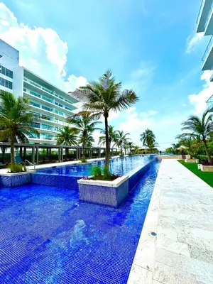 a swimming pool with palm trees and a building at Apartamento con piscina gigante y acceso directo al mar in Cartagena de Indias
