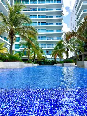 a large swimming pool with palm trees and a tall building at Apartamento con piscina gigante y acceso directo al mar in Cartagena de Indias