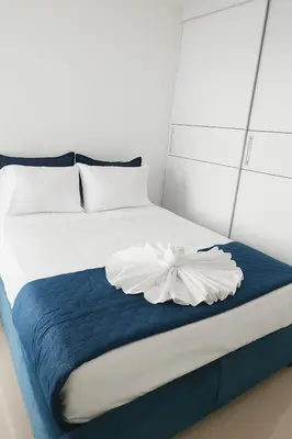 a white bed with a blue blanket and a white flower on it at Cartagena Apartamento completo vista al mar in Cartagena de Indias