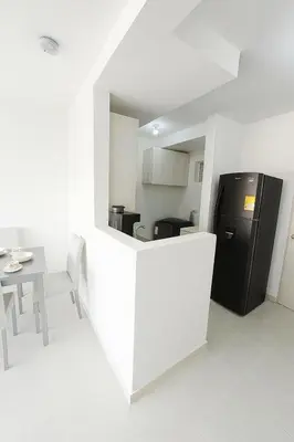 a white kitchen with a black refrigerator and a table at Cartagena Apartamento completo vista al mar in Cartagena de Indias