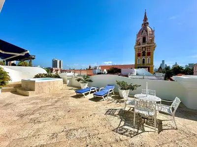 a patio with chairs and a table and a clock tower at By Calamari Homes - Ayos 206 - Walled City in Cartagena de Indias
