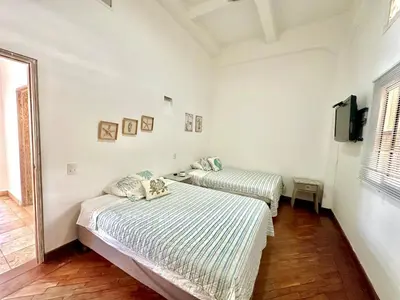 two beds in a white room with a tv at By Calamari Homes - Ayos 206 - Walled City in Cartagena de Indias