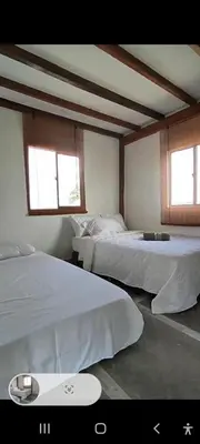 two beds in a room with two windows at Hostal Casa Adela