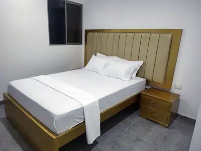 a bed with white sheets and a wooden headboard at Hotel La Dorada Sincelejo in Sincelejo