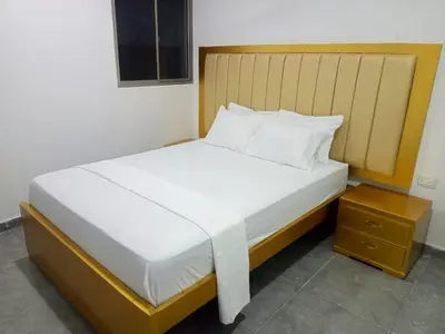 a bedroom with a large white bed with a wooden headboard at Hotel La Dorada Sincelejo in Sincelejo