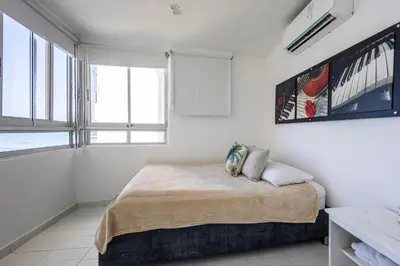a white bedroom with a bed with two pillows on it at Caribbean Paradise - Apartamento con salida directa a la playa in Cartagena de Indias