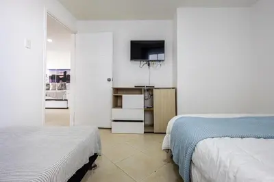 a bedroom with two beds and a tv on the wall at Caribbean Paradise - Apartamento con salida directa a la playa in Cartagena de Indias