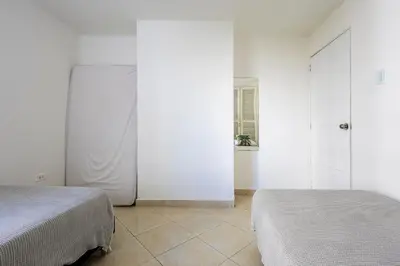 two beds in a room with white walls at Caribbean Paradise - Apartamento con salida directa a la playa in Cartagena de Indias