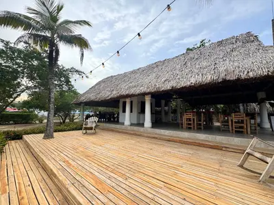 a pavilion with a wooden deck and a thatch roof at Hostal nido tortuga in San Antero