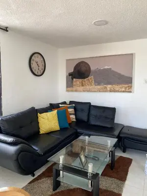 a living room with a black leather couch and a clock at White House in Cartagena de Indias