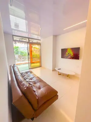 a living room with a brown leather couch and a table at CALA Estancias Urbanas, Apartamentos & Suites in Barranquilla