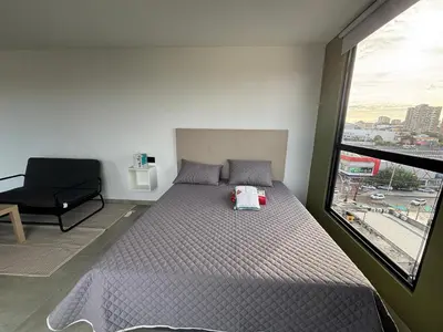 a bedroom with a bed and a chair and a window at Delux Suite Coral Tower in Barranquilla