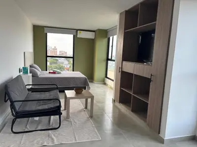 a bedroom with a bed and a chair and a television at Delux Suite Coral Tower in Barranquilla