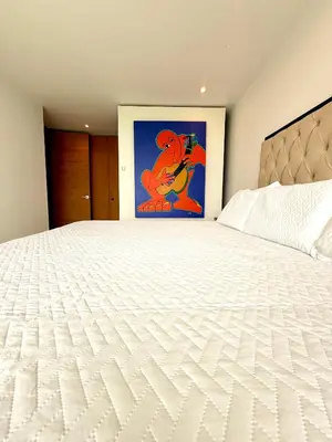 a large white bed in a bedroom with a painting at Karibmed Cartagena in Cartagena de Indias