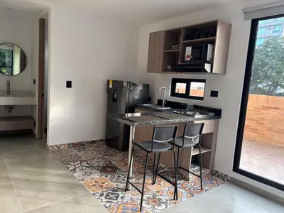 a kitchen with a bar with stools and a sink at Deluxe Suite with Terrace in Barranquilla