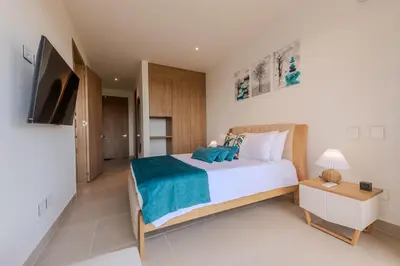 a bedroom with a large bed and a television at Cartagena getaway - Laguna Cristalina - 2BR - 7 pax in Cartagena de Indias