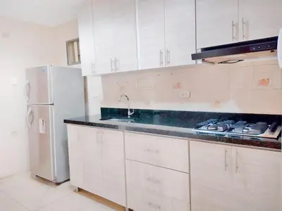 a kitchen with white cabinets and a white refrigerator at Caribbean Sunset - Apartamento con salida a la playa in Cartagena de Indias