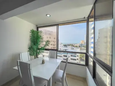a dining room with a white table and chairs and a large window at Caribbean Sunset - Apartamento con salida a la playa in Cartagena de Indias