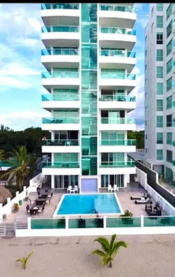 a large building with a swimming pool in front of it at 3BR AC Amazing View and Pool, Best sunset ever in Coveñas
