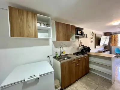 a small kitchen with wooden cabinets and a white refrigerator at Moderno apartamento privado con parqueadero in Barranquilla