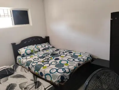 a bedroom with a bed with a comforter and a fan at La casa de la abuela cartagena in Cartagena de Indias