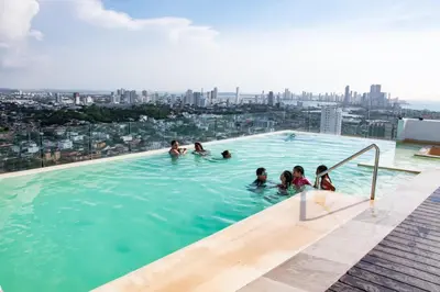 a group of people in a swimming pool on the roof of a building at Hermoso Apartamento con Piscina 1 Habitacion CMC66 in Cartagena de Indias