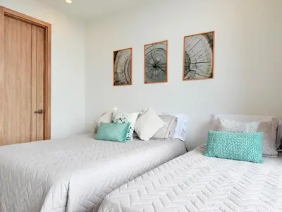 two beds in a white room with three pictures on the wall at Premium Apartment - Beachfront - Luxury condo in Cartagena de Indias