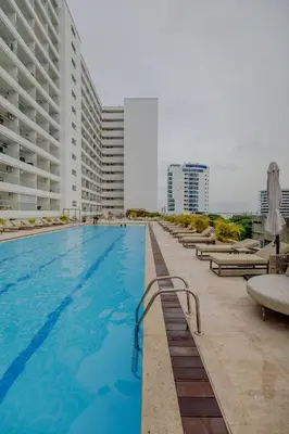 a large swimming pool with lounge chairs and buildings at Encantador y moderno estudio con piscina a pasos del aeropuerto in Cartagena de Indias