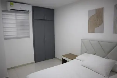 a bedroom with a white bed and a small table at Cartagena Piscina, playa y cerca centro Historico in Cartagena de Indias