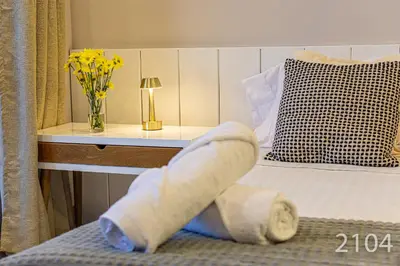 a towel sitting on a bed with a vase of flowers at Santa Marina Apartments and Beach Club by Xarm Apartments in Santa Marta