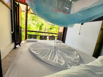 a bed with an umbrella on top of it at El Hamaquero Hostal EcoNativo in Isla Grande
