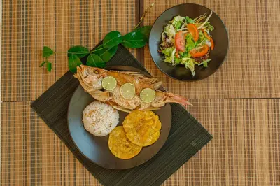 two plates of food with a fish and salad and chips at El Hamaquero Hostal EcoNativo in Isla Grande