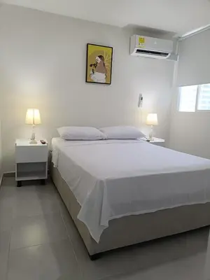 a white bedroom with a large bed and two lamps at Apartamento en Cartagena amoblado con vista al mar in Cartagena de Indias
